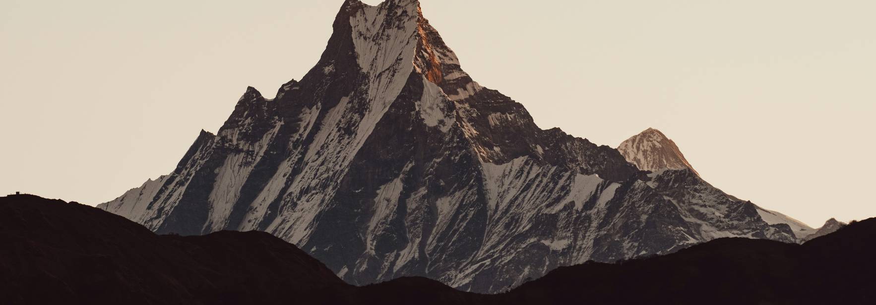 Una imponente montaña con picos nevados al atardecer.