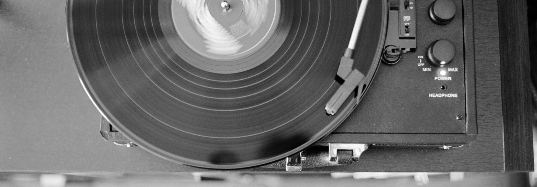 Un tocadiscos reproduciendo un disco de vinilo en blanco y negro.