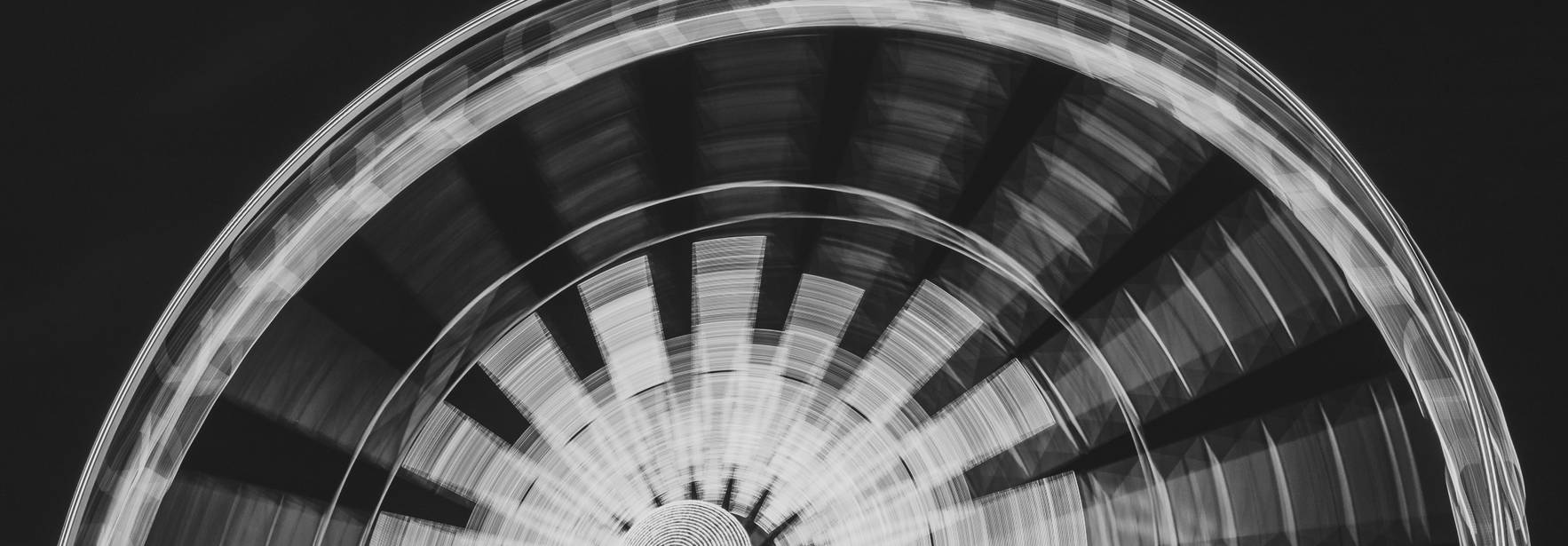 Una fotografía en blanco y negro de una rueda de la fortuna en movimiento.