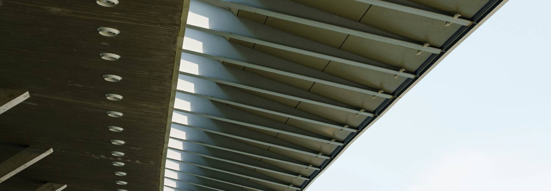 La imagen muestra la estructura inferior de un puente con luces empotradas y un diseño moderno.