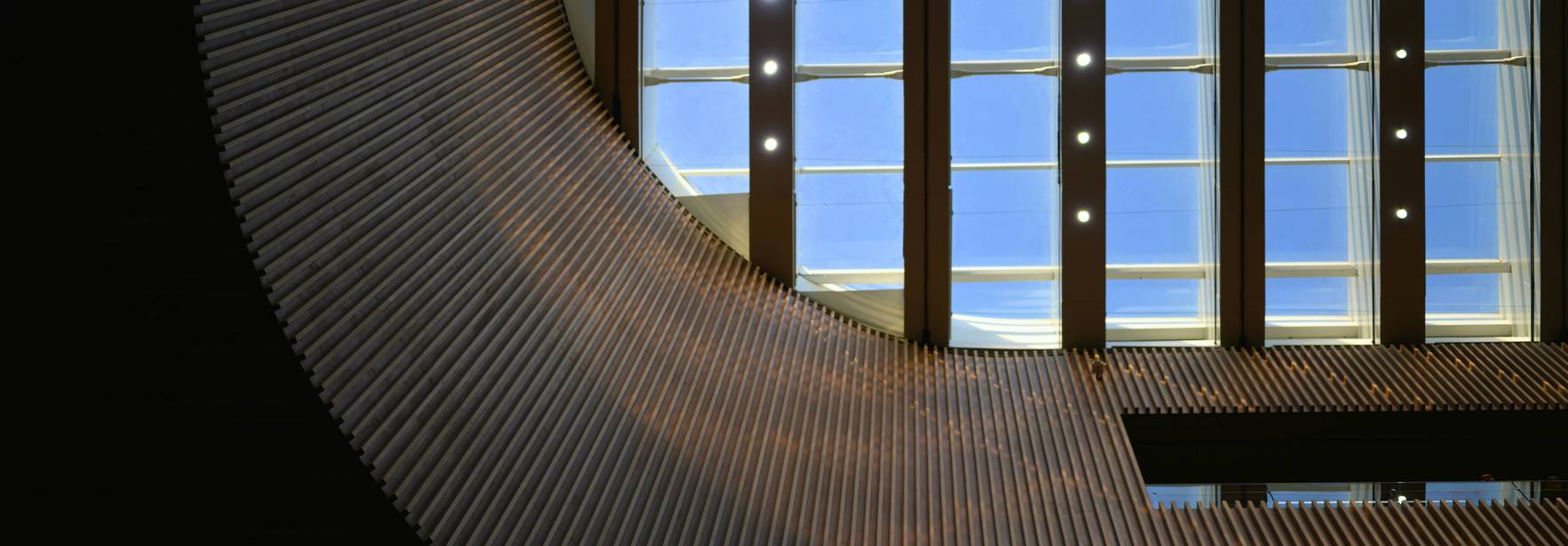 Imagen que muestra un diseño arquitectónico moderno con una estructura curvada y una gran ventana que permite la entrada de luz natural.