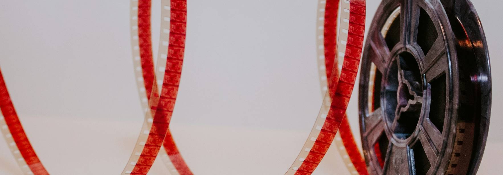 La imagen muestra una bobina de película con una cinta roja que se desenrolla en forma de espiral.