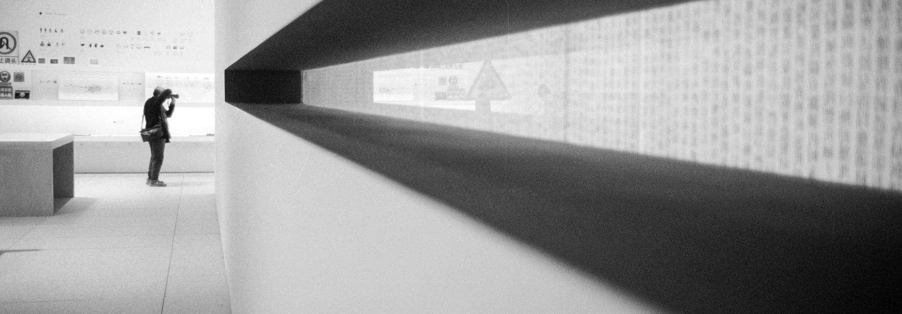 Una persona fotografía una pared en un entorno minimalista y contemporáneo.
