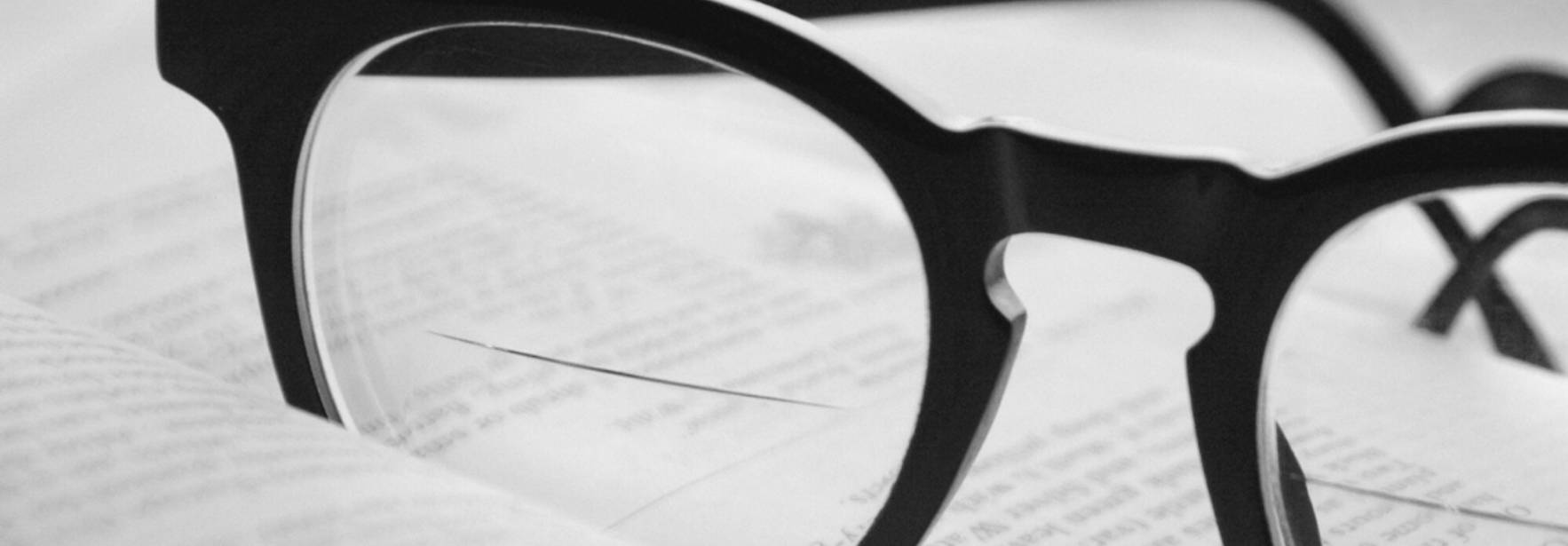 Unas gafas sobre un libro abierto, con un fondo desenfocado.