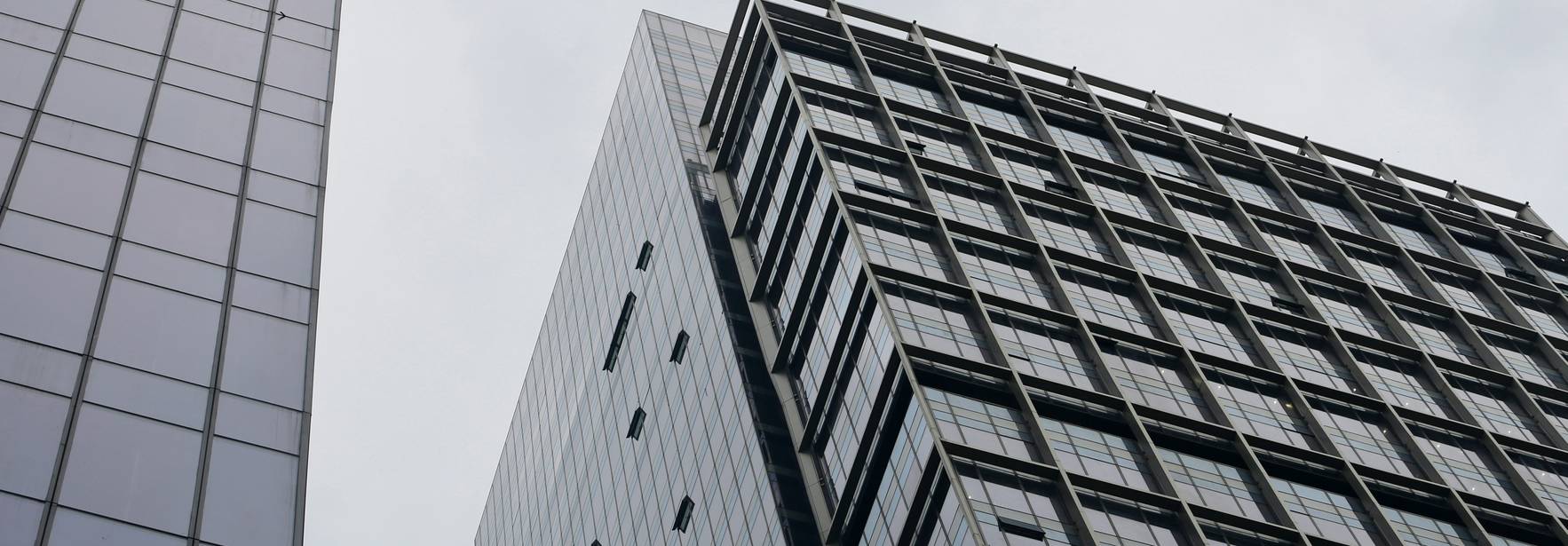 La imagen muestra un ángulo bajo de edificios de vidrio en un día nublado.