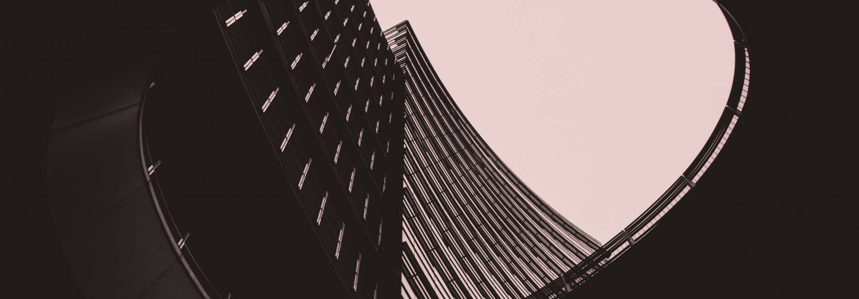 Una perspectiva arquitectónica que muestra la curvatura de un edificio moderno rodeado de líneas verticales y un cielo suave.