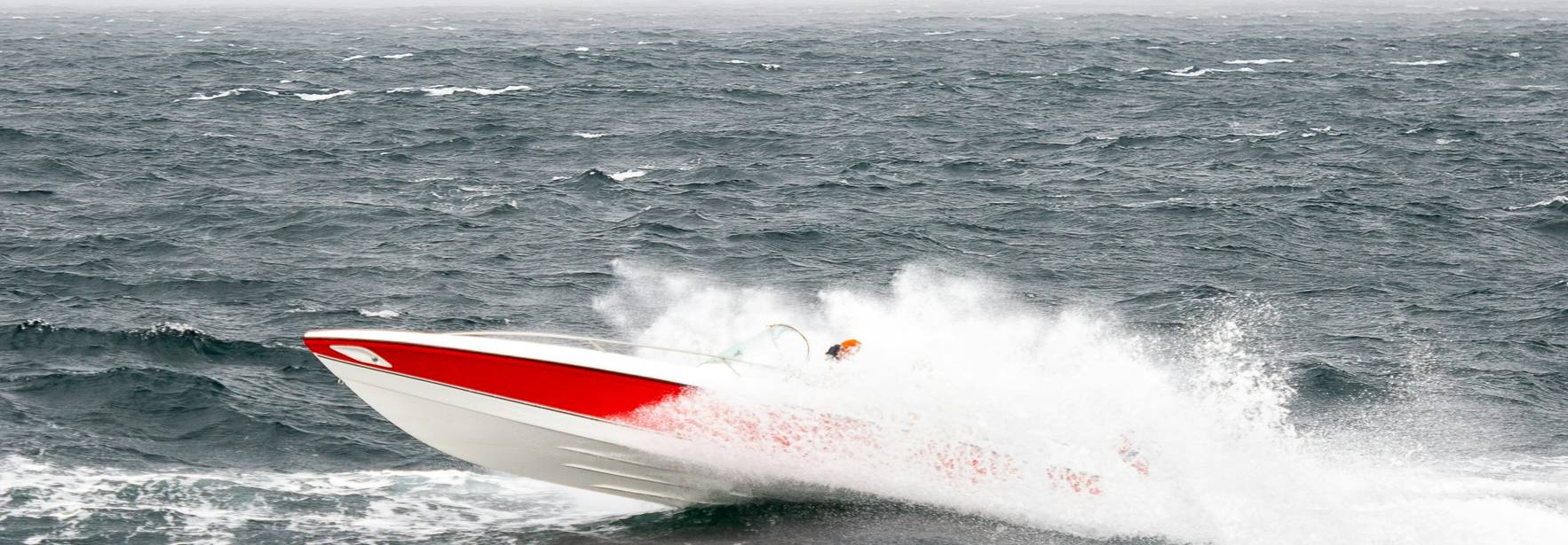 Un barco de motor surca las aguas agitadas del mar produciendo grandes olas.