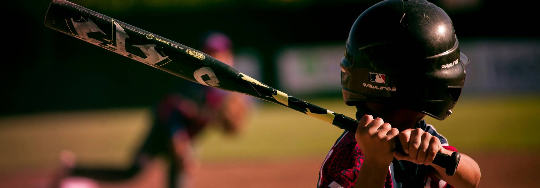 Un joven jugador de béisbol se prepara para batear una pelota lanzada por su compañero.