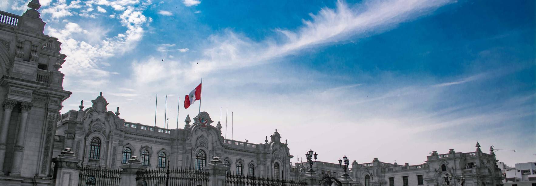 Una vista del Palacio de Gobierno en Lima, Perú, bajo un cielo azul con nubes.