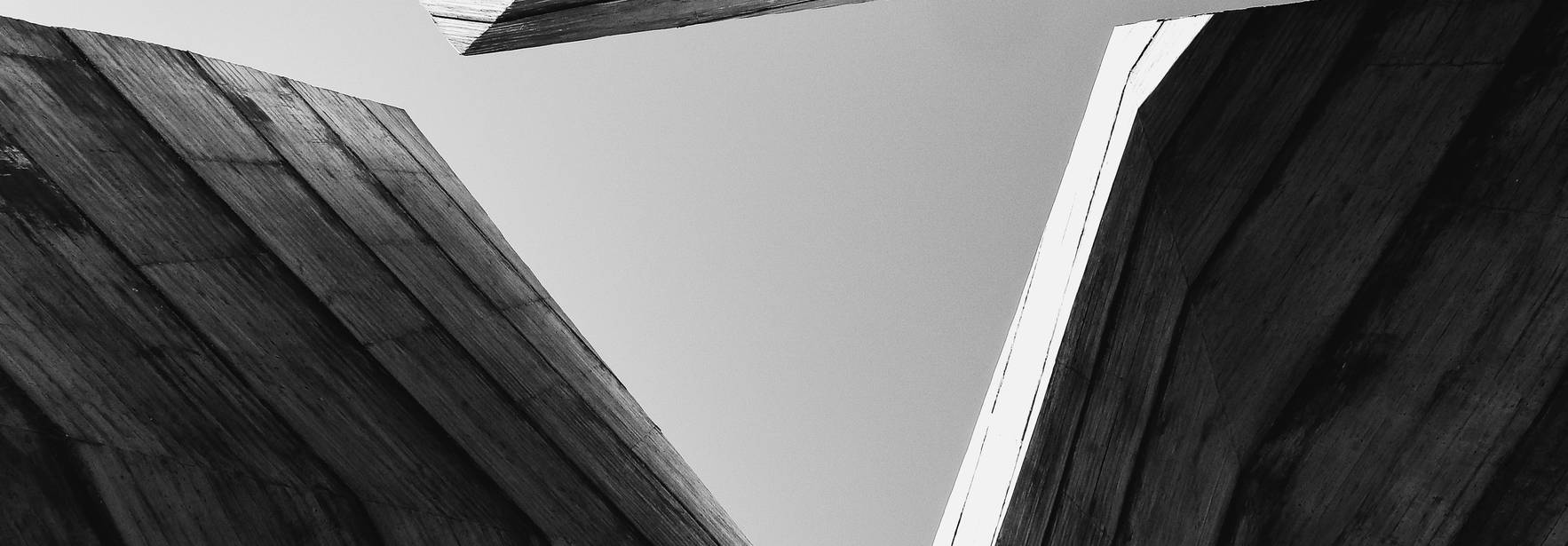 La imagen muestra una vista desde abajo de estructuras geométricas de madera en perspectiva.
