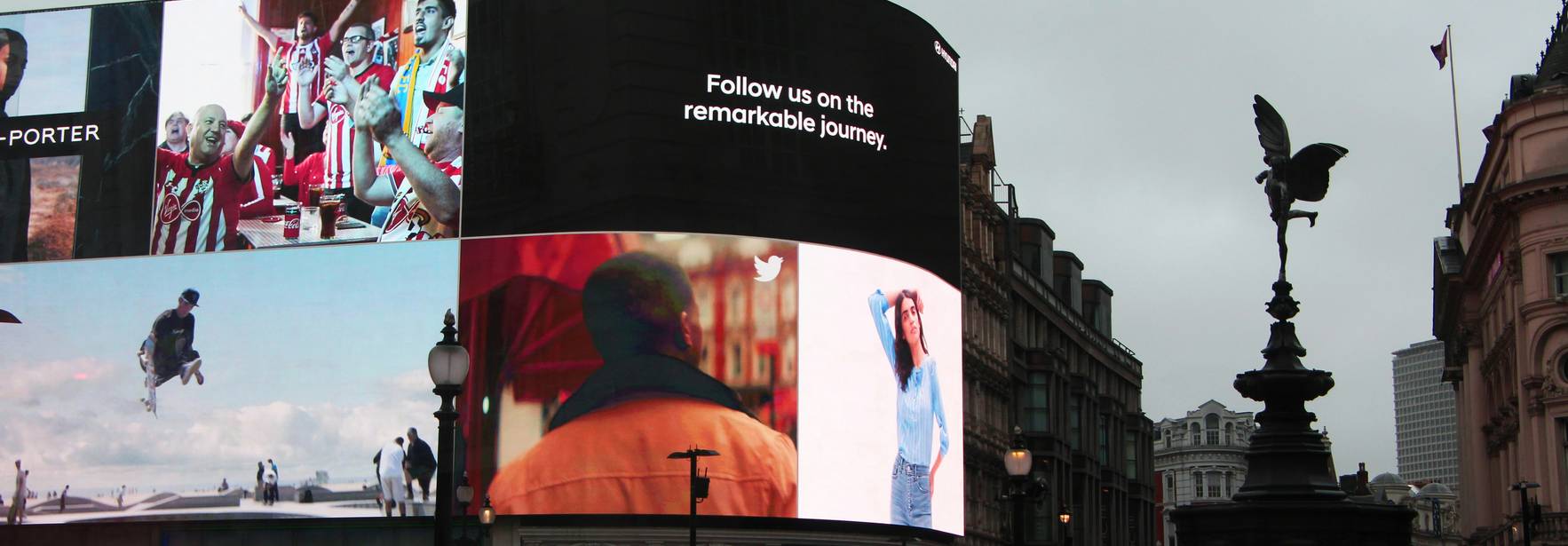 Una vista urbana con pantallas publicitarias iluminadas y una fuente en el frente.