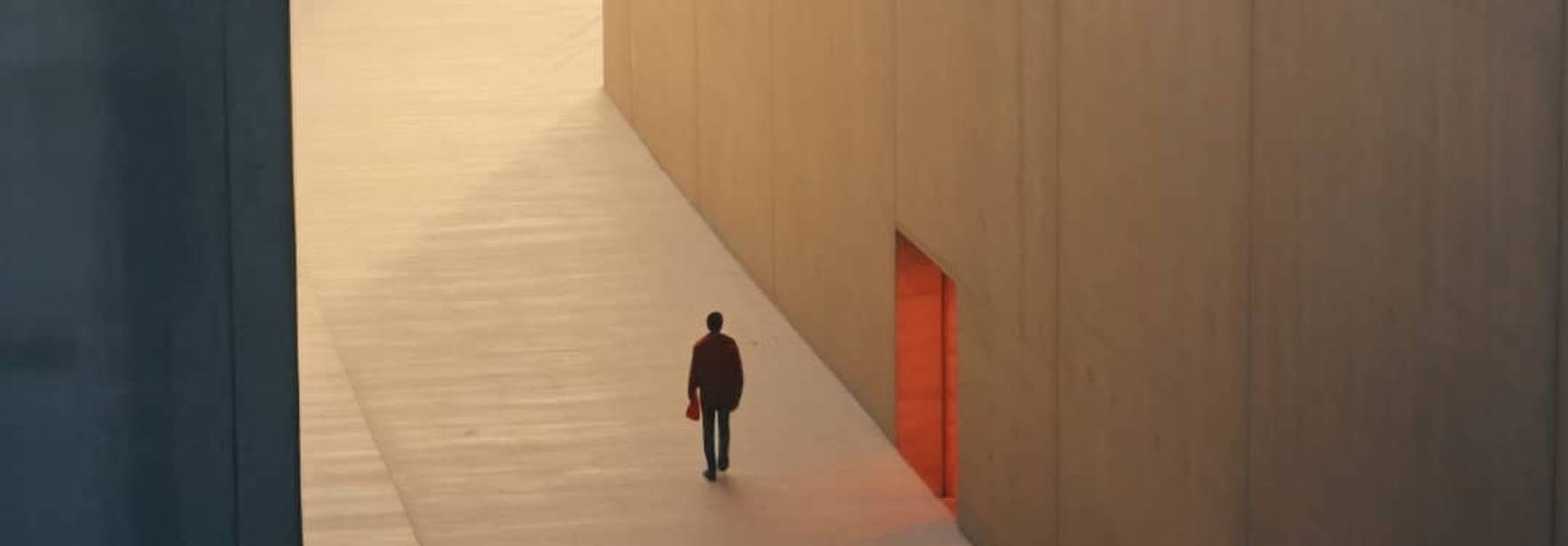 Un hombre camina solo por una pasarela en un ambiente minimalista y casi etéreo.