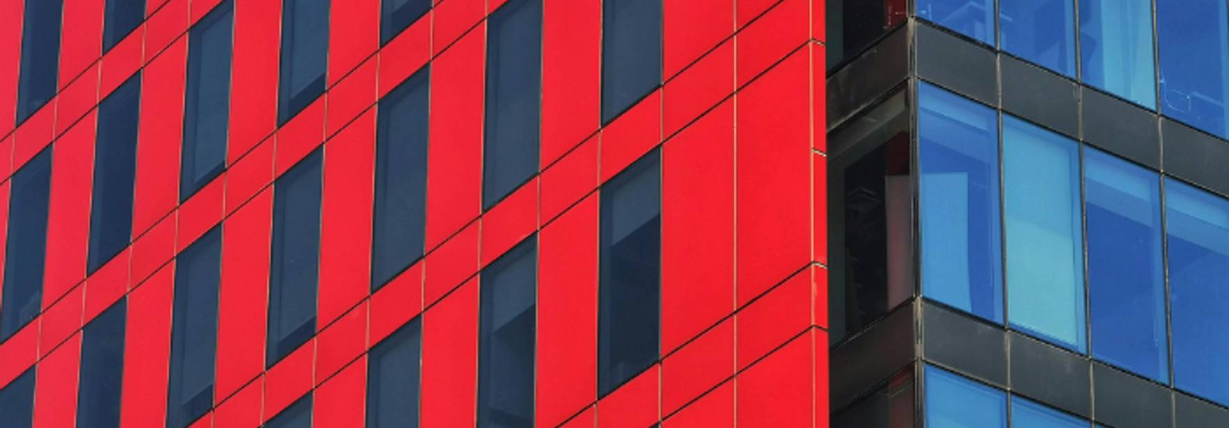 La imagen muestra un edificio moderno con una fachada de colores rojo y azul.