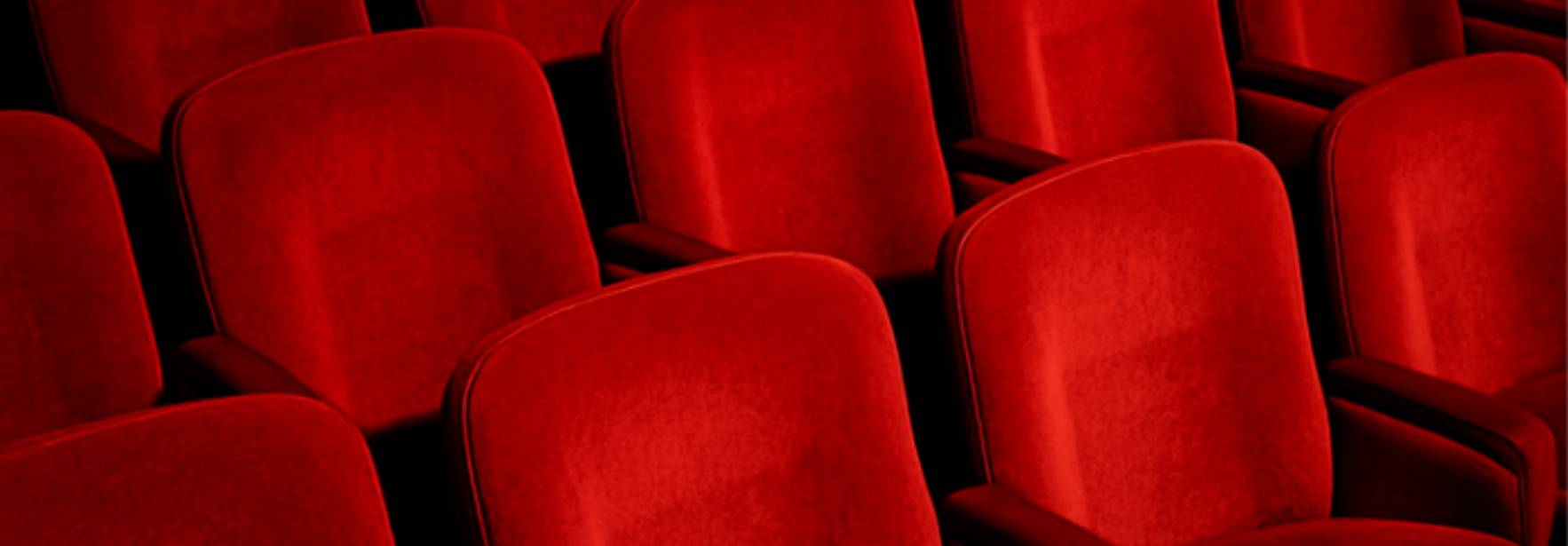 Un conjunto de asientos rojos dispuestos en un teatro.