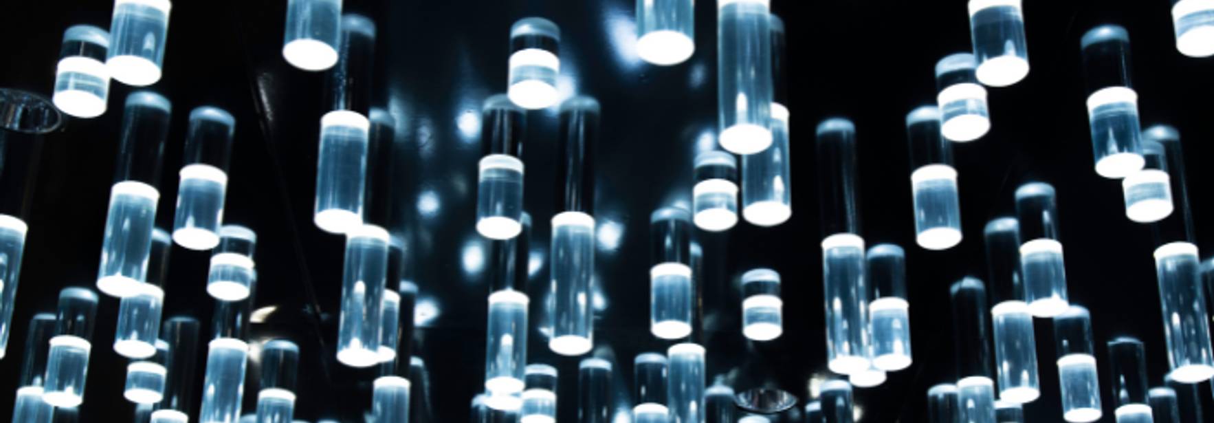 La imagen muestra una serie de luces colgantes en un fondo oscuro que crean un efecto visual atractivo.