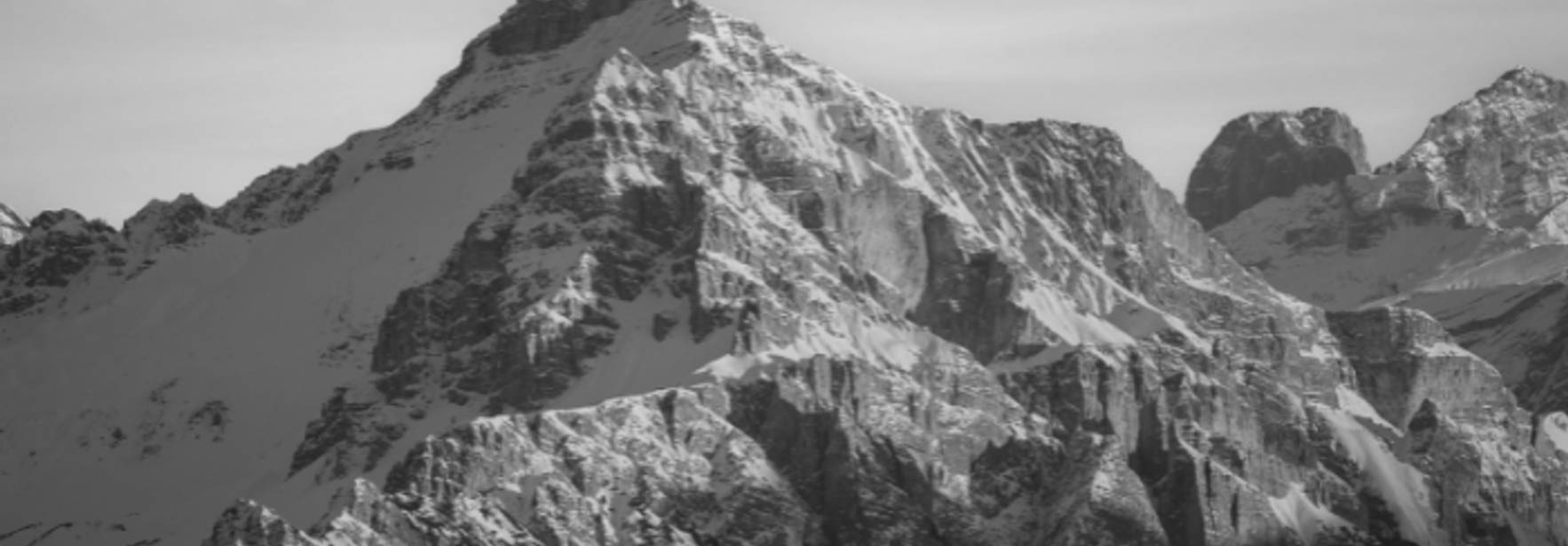 Una montaña imponente cubierta de nieve en un paisaje en blanco y negro.
