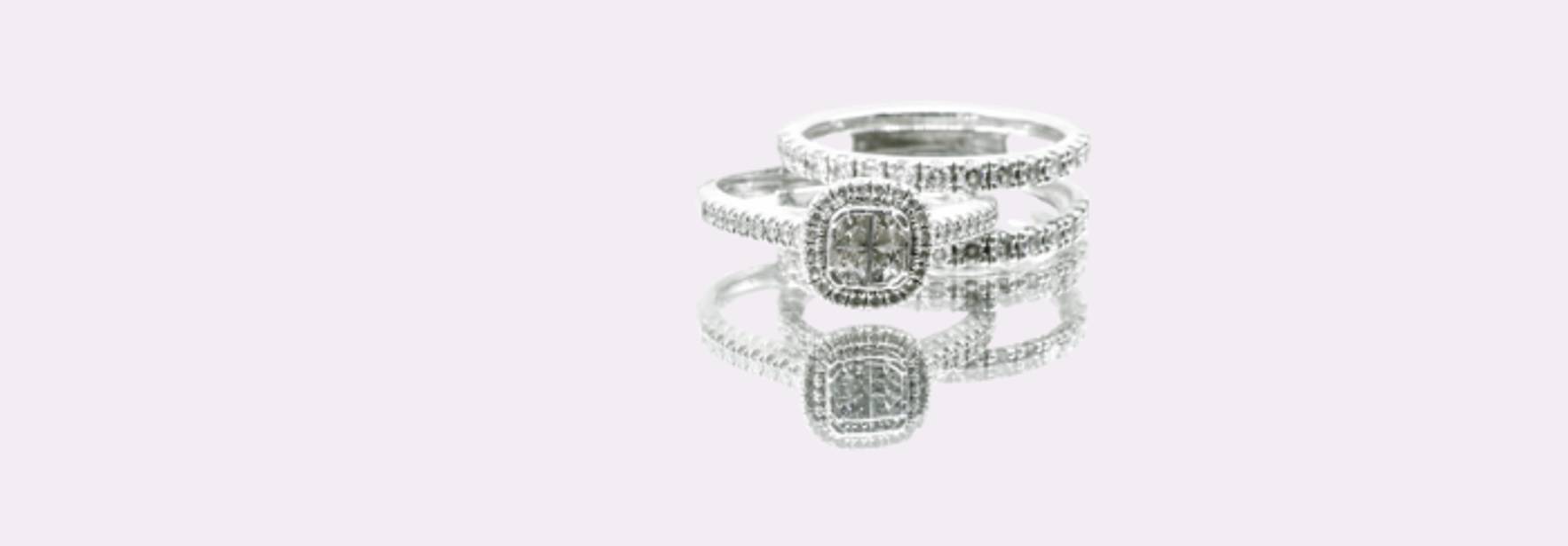 Un conjunto de anillos de boda de plata con diamantes que brillan sobre un fondo claro.