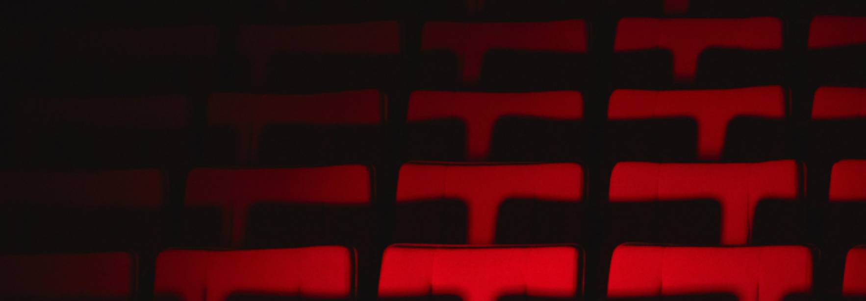 Una fila de asientos vacíos iluminados en rojo.