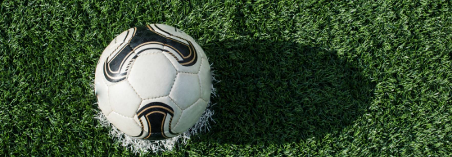 Un balón de fútbol descansa sobre un campo verde.
