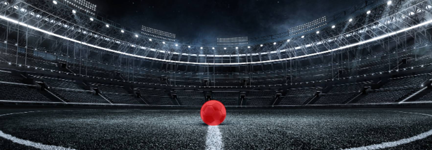 Una pelota roja se encuentra en el centro de un estadio de fútbol vacío y oscuro.