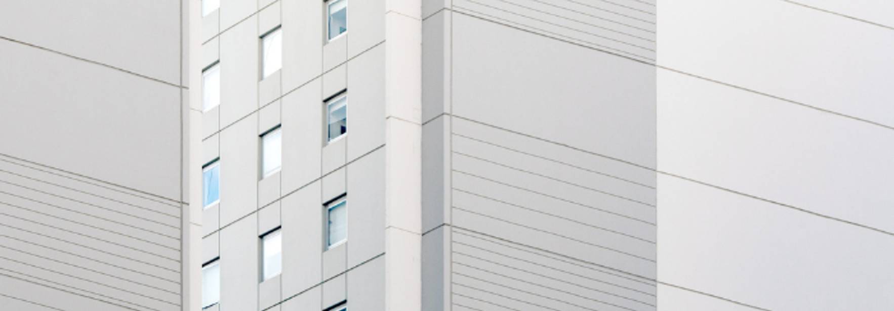 La imagen muestra una fachada de un edificio moderno con líneas horizontales y ventanas.