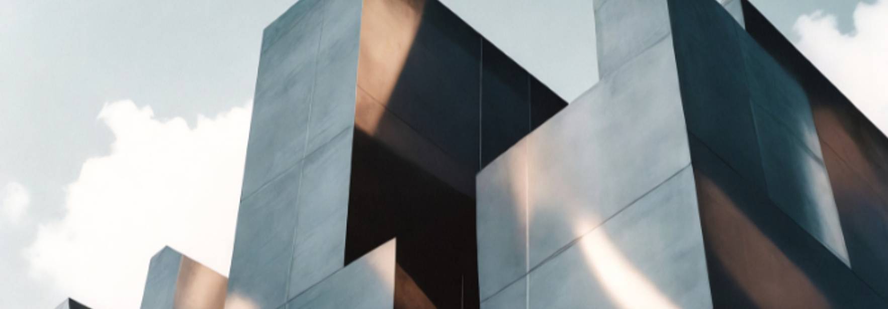 La imagen muestra un grupo de estructuras arquitectónicas modernas y angulares con un acabado metálico que refleja la luz.