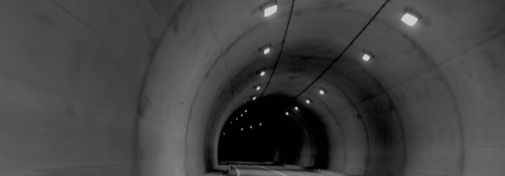 Un túnel oscuro con luces en las paredes y un camino que se curva hacia adelante.