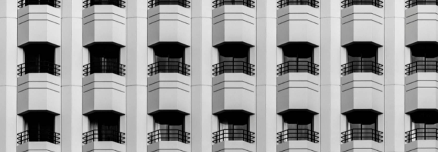 Imagen en blanco y negro de un patrón repetitivo de ventanas de un edificio moderno.