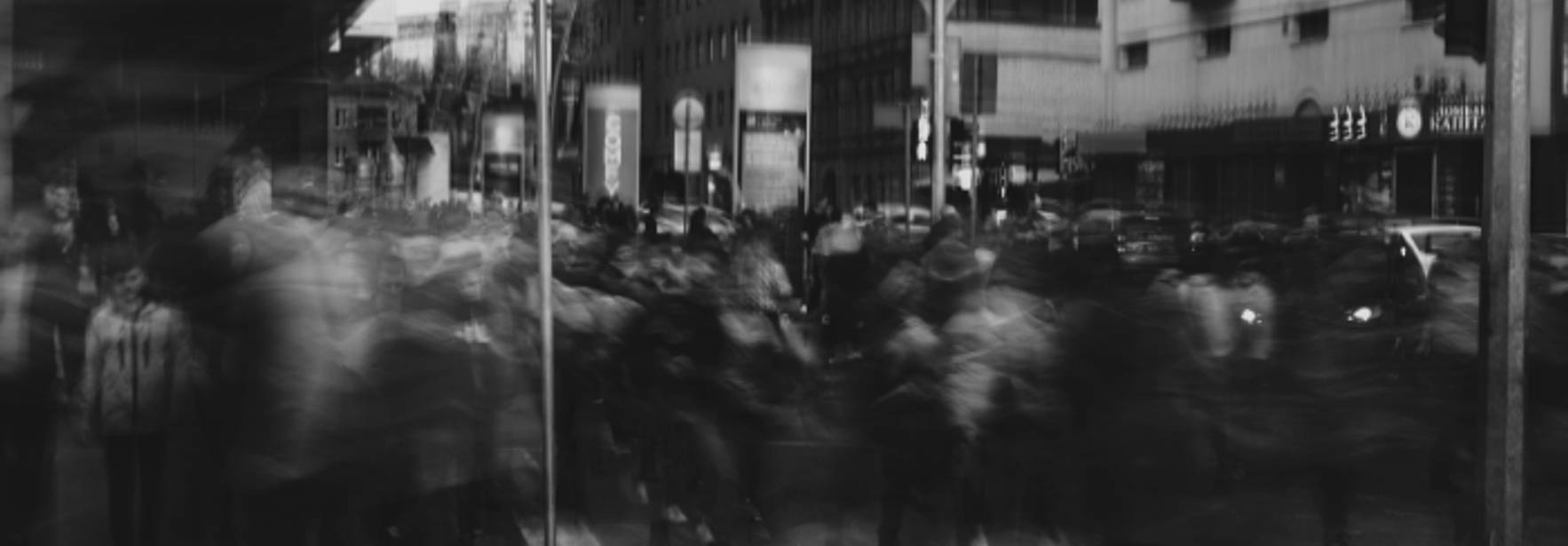 Una multitud de personas se mueve en una calle urbana en un ambiente borroso.