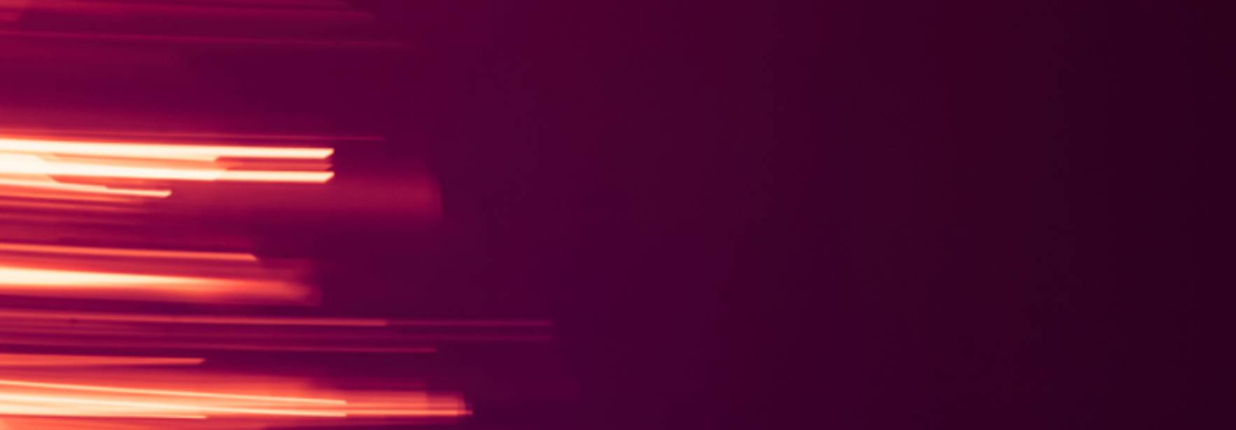 Un fondo abstracto con líneas de luz en tonos rojos y púrpuras.