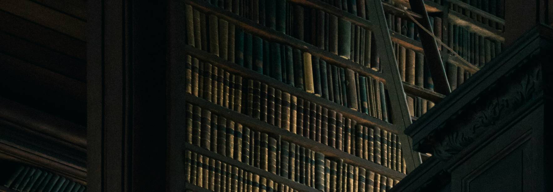 Una biblioteca antigua con estanterías repletas de libros en un ambiente iluminado sutilmente.