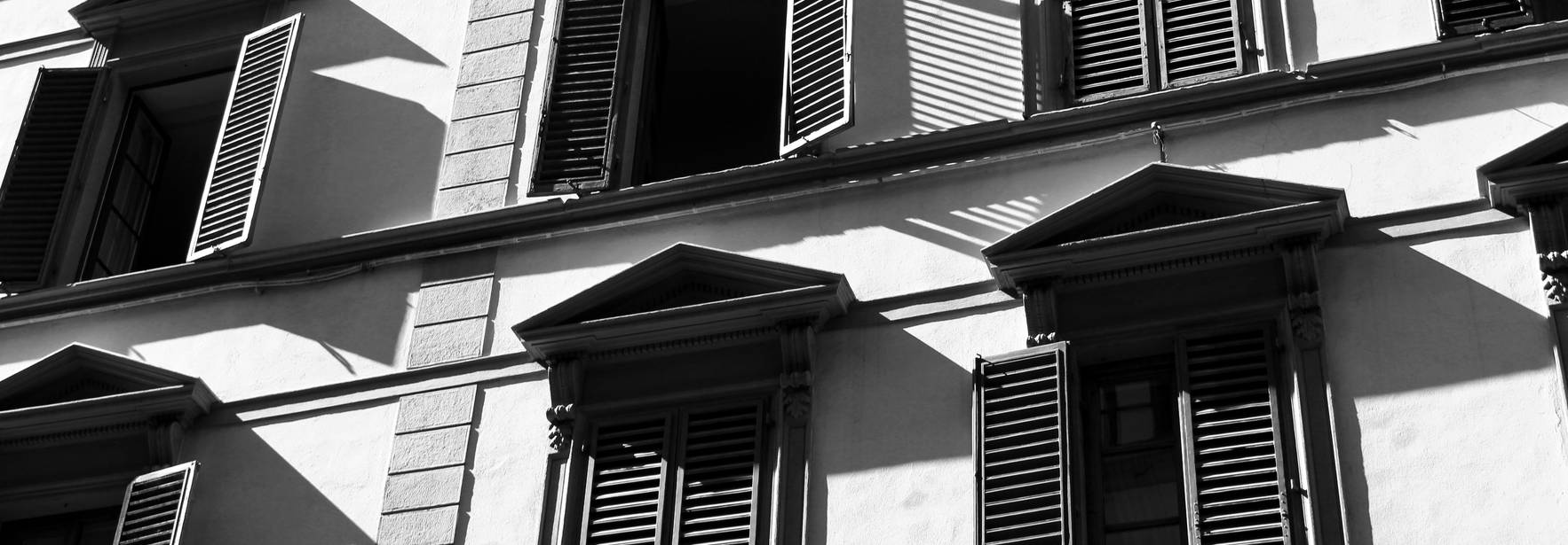 Edificio con ventanas y persianas en contraste de luces y sombras.