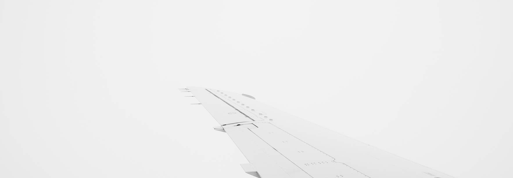 Una vista en blanco y negro de un ala de avión con un fondo nublado.
