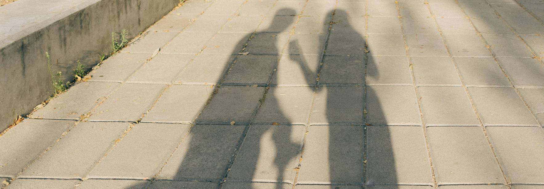 Las sombras de dos personas se proyectan sobre un suelo de loseta.
