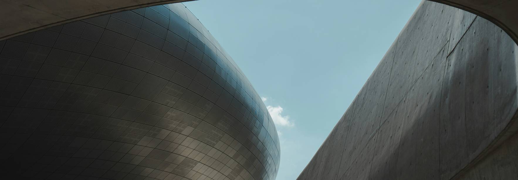 La imagen muestra una estructura arquitectónica moderna con un cielo azul visible a través de un arco.