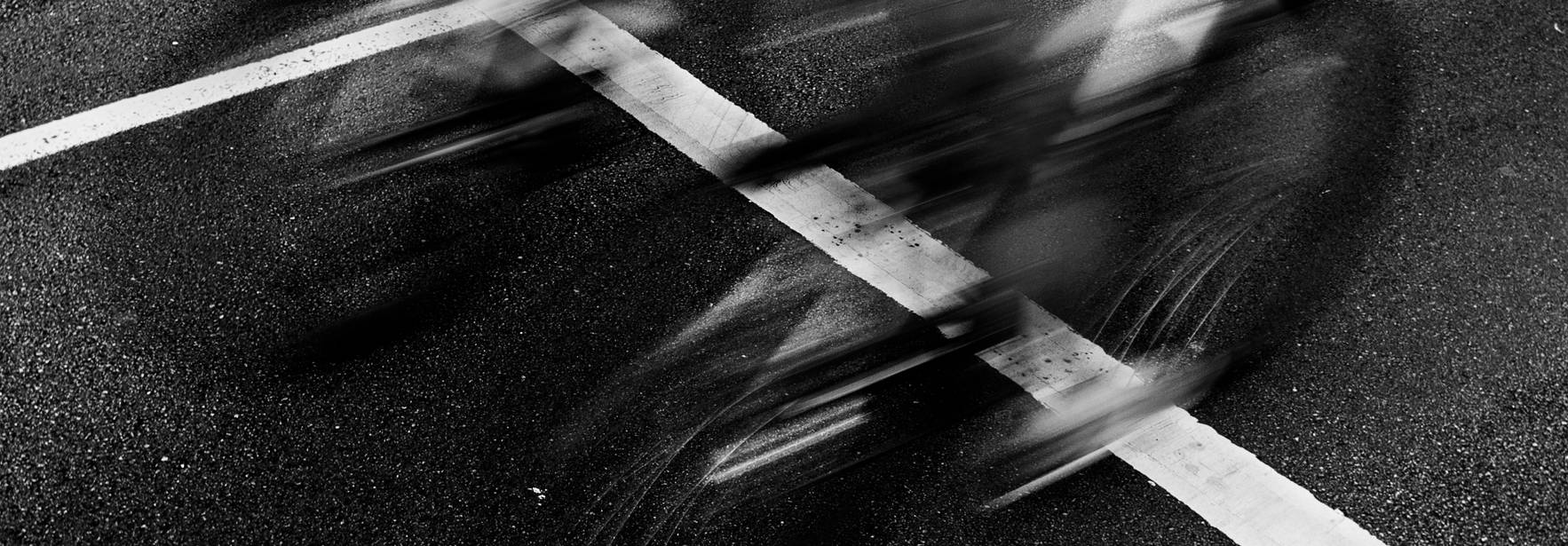 Una imagen en blanco y negro que muestra bicicletas en movimiento cruzando una línea en la carretera.