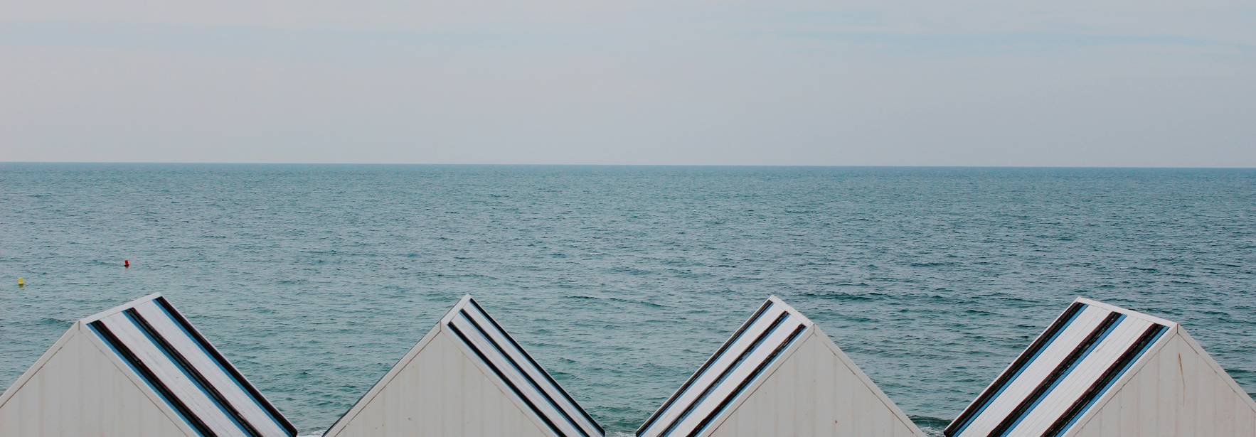 Imagen de una serie de casetas de playa frente al mar.
