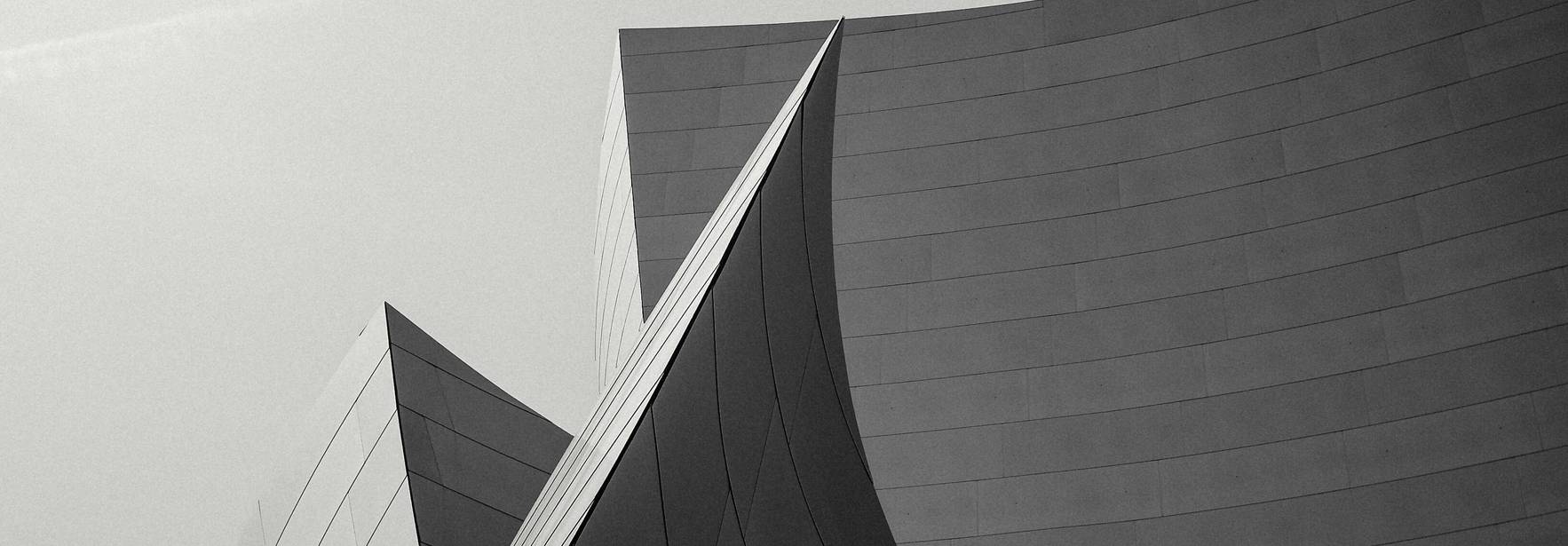 La imagen muestra un conjunto arquitectónico con formas curvilíneas y superficies metálicas en blanco y negro.