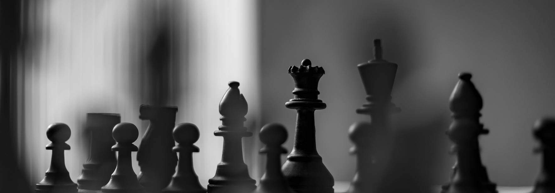 Una partida de ajedrez en blanco y negro con piezas de diferentes formas alineadas en el tablero.