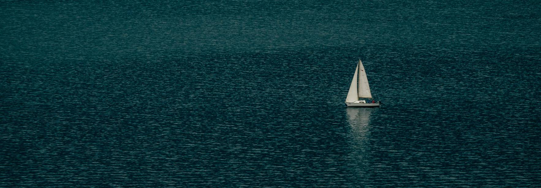 Un velero navega solo en un mar tranquilo.