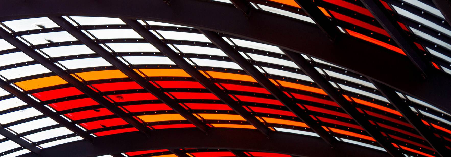 Una estructura arquitectónica con paneles de vidrio en tonos rojos, naranjas y amarillos.