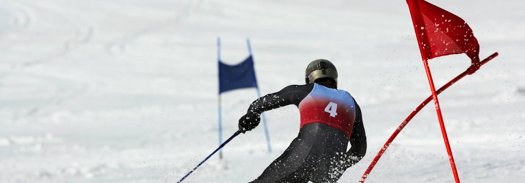 Un esquiador compitiendo en una pista nevada, esquivando puertas de slalom.