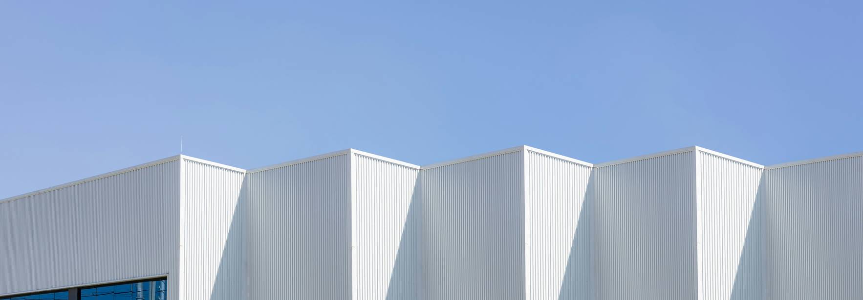 Edificio moderno con un diseño angular y una fachada blanca bajo un cielo azul claro.