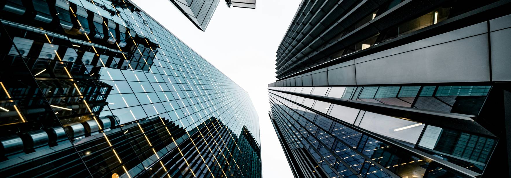 Vista desde abajo de edificios modernos y altos con reflejos de vidrio.