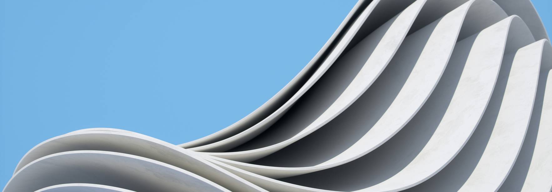 Una escultura arquitectónica que presenta un diseño ondulado y moderno en tonos blancos contra un cielo azul.