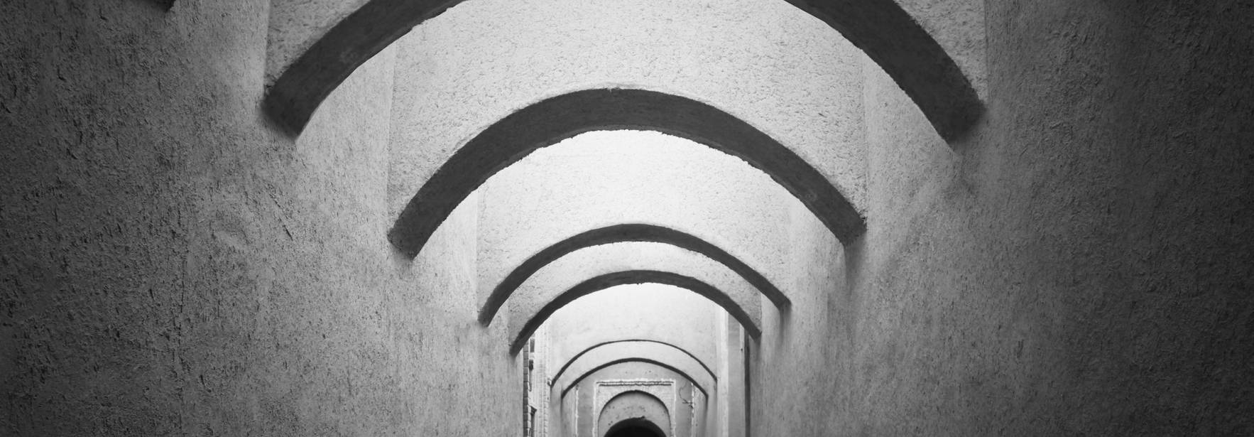 Un pasillo oscuro con arcos iluminados en el techo.