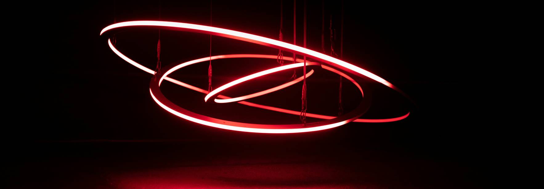 Una instalación de luces rojas en un entorno oscuro que parece girar en el aire.