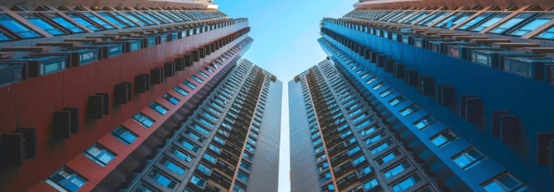 Imagen que muestra un ángulo de vista hacia arriba entre dos edificios altos de diferentes colores.