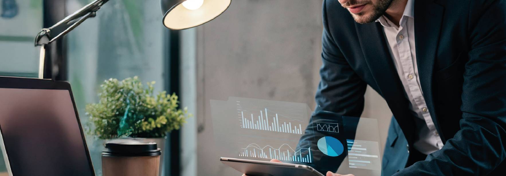 Un hombre de negocios revisa datos en una tablet mientras trabaja en una oficina moderna.