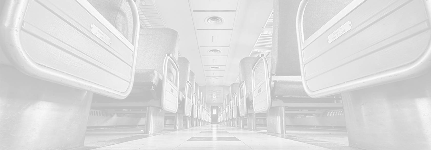 El interior de un vagón de tren con asientos vacíos y una perspectiva en profundidad.